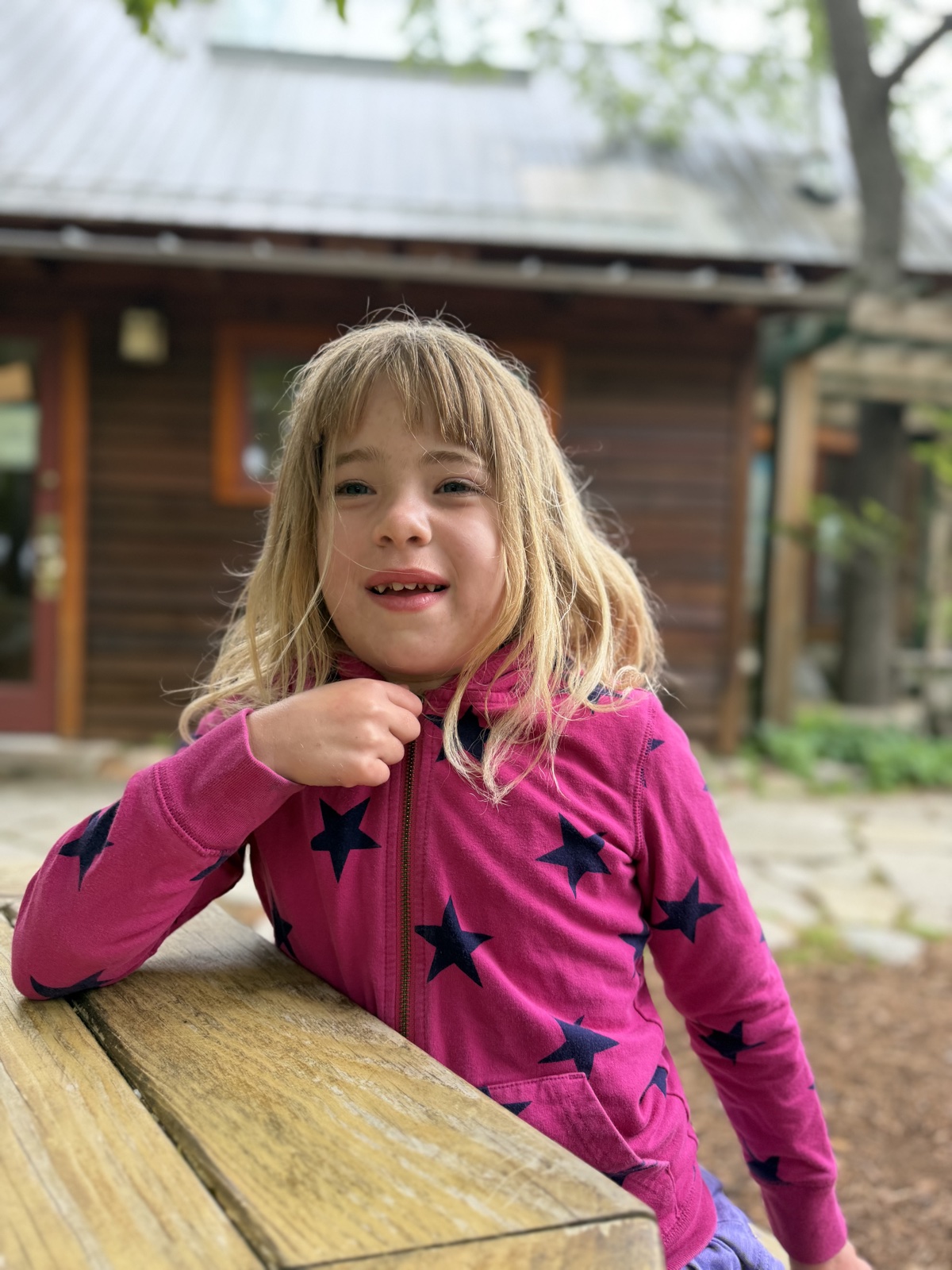 Elle smiling outdoors at a picnic table